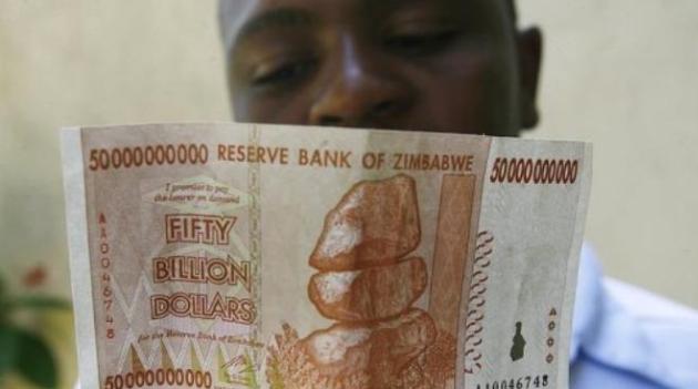 A Zimbabwean looks at a 50 billion dollar bank note/AFP