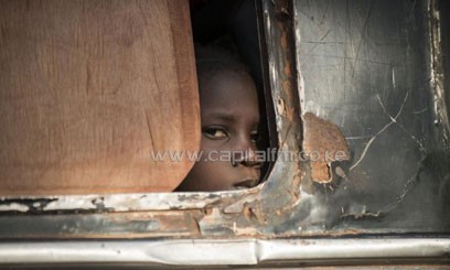 A girl looks out from a bus as Malian soldiers prepare to check the vehicle and passengers at a checkpoint in the city of Niono, on January 18, 2013/AFP