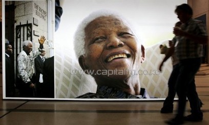 People walk past a giant picture of Nelson Mandela in Cape Town on June 27, 2013/AFP