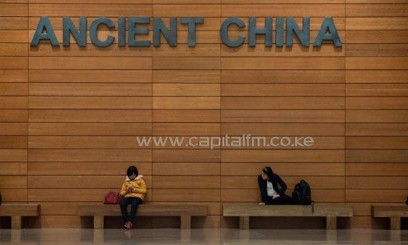 People sit beneath a sign at a museum in Beijing on April 23, 2013/AFP