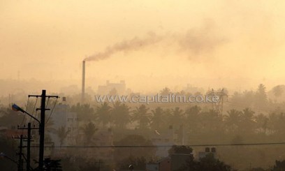 A factory chimney belches smoke in a residential area as haze casts a blanket over Bangalore/AFP