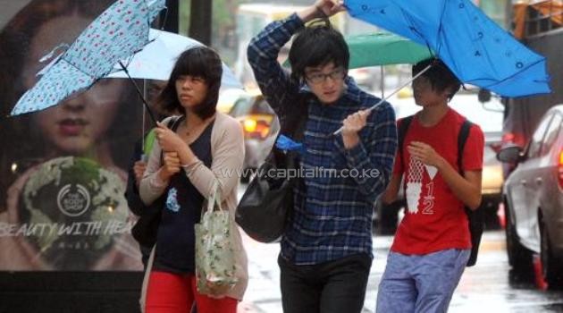 Pedestrians walk through strong winds and rain caused by Typhoon Fitow in Taipei on October 6, 2013/AFP