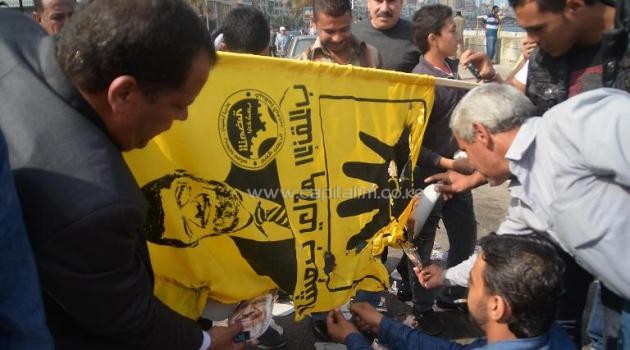 A flag with the image of Mohamed Morsi is burnt by supporters of Egypt's military-installed authorities in Alexandria on November 4, 2013/AFP