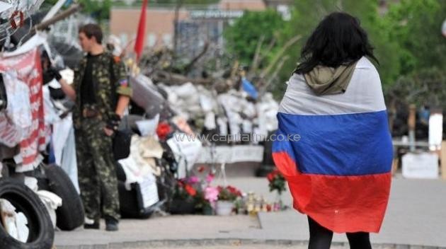 A woman wrapped in a Russian flag walks at a barricade outside the regional state building seized by separatists in the centre of the eastern Ukrainian city of Donetsk/AFP