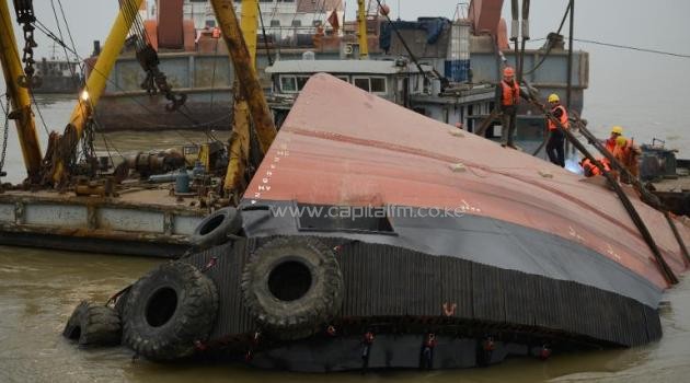 Members of a rescue team (in orange) look at a section of the hull of a tugboat which sank on a trial voyage in Jingjiang, in east China's Jiangsu province, on January 16, 2015/AFP