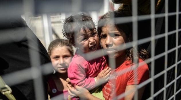 Syrian refugees wait behind a fence prior to go back to the northern Syrian town of Tal Abyad at the Turkish border post of Akcakale, the province of Sanliurfa, on June 17, 2015/AFP