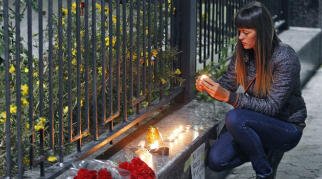 A woman lights a candle outside the Russian embassy in Kiev on October 31, 2015, to commemorate passengers that died in the crash of Kogalymavia flight 9268 © AFP
