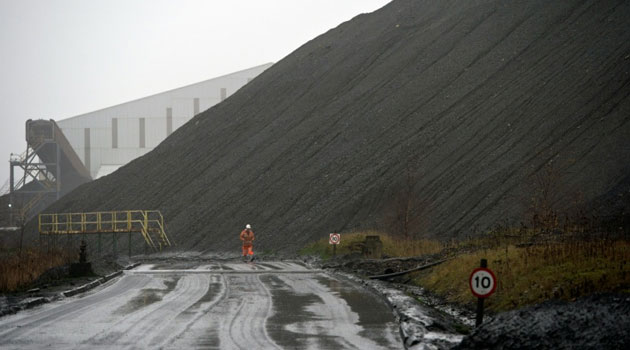 A mine worker walks past a slag heap at the entrance to Kellingley Colliery, the last deep coal mine operating in Britain near Knottingley, northern England on December 15, 2015 © AFP