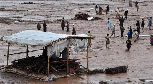Flood waters rush through a Pakistani market area as vendors and residents scramble to save their possessions on the outskirts of Peshawar on April 3, 2016/AFP