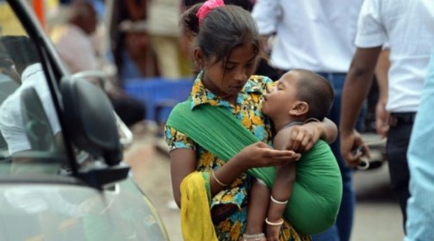 A girl carrying a toddler counts money collected by begging from commuters at a busy traffic intersection in Mumbai/AFP