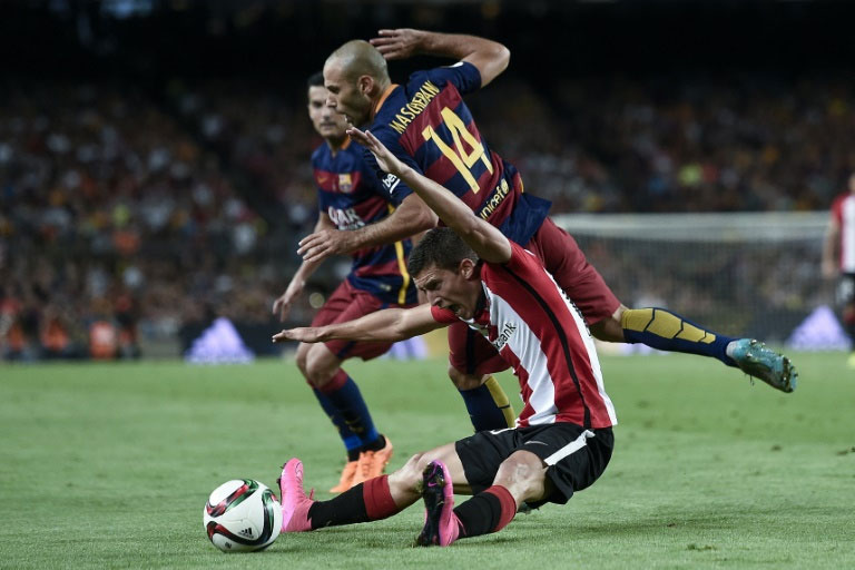 Athletic Bilbao's Oscar de Marcos (bottom) fights for the ball with Barcelona's Javier Mascherano during their Spanish Super Cup match, at the Camp Nou stadium in Barcelona, on August 17, 2015. PHOTO/AFP