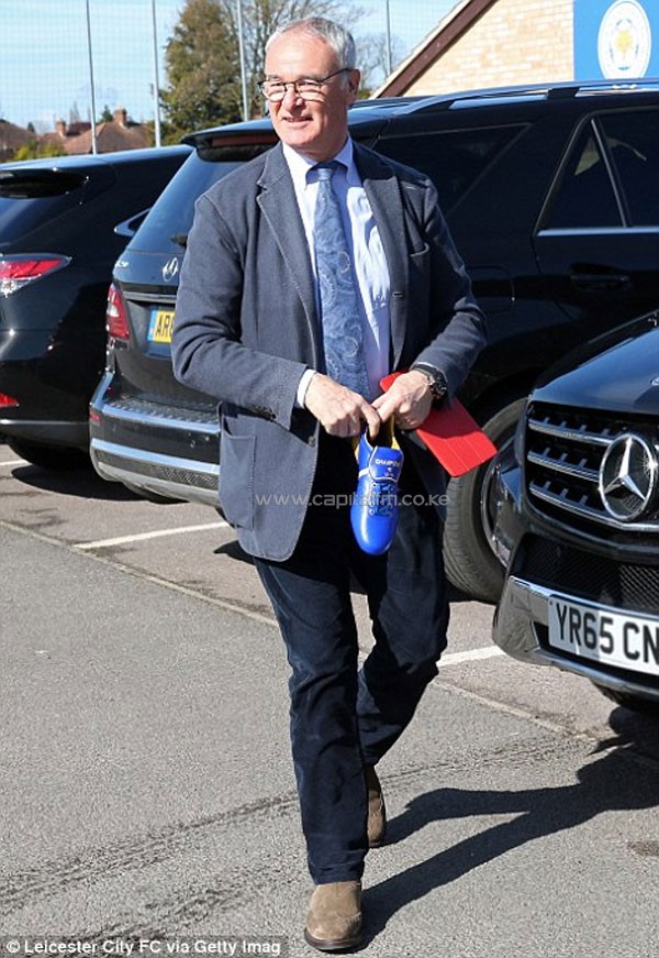 Ranieri holds a blue boot with the words 'Champions 15-16' on it after returning from Italy on Monday night