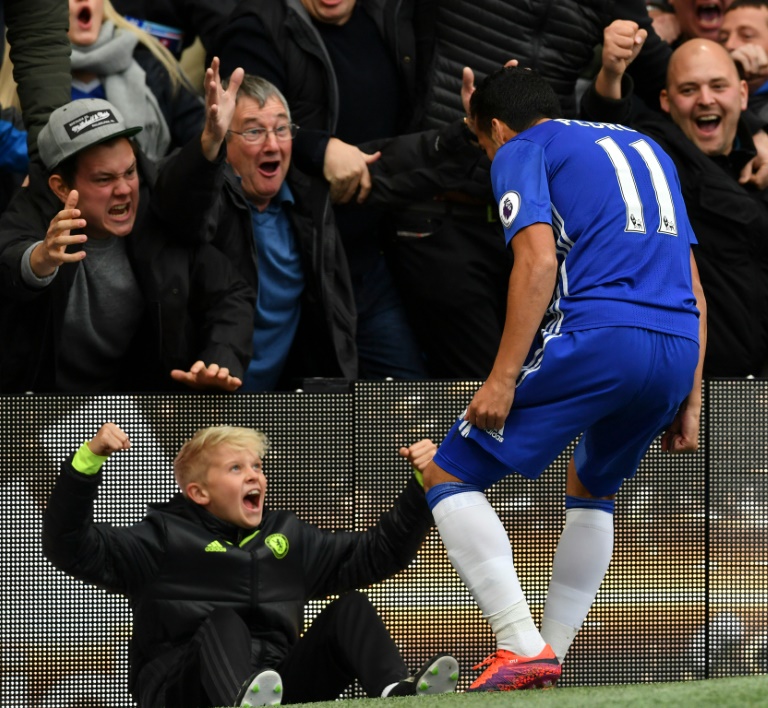 Chelsea's midfielder Pedro celebrates with ball-boy and supporters after scoring against Manchester United at Stamford Bridge in London on October 23, 2016
