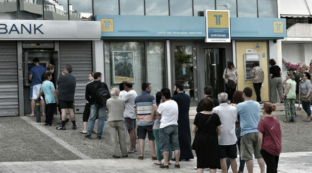 People stand in a queue to use ATM machines to withdraw cash at a bank in Athens on June 27, 2015/AFP
