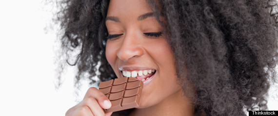 Young woman eating a delicious piece of chocolate bar