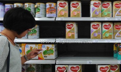 A woman checks the price of Dumex baby milk formula at a store in Yichang, China, August 5, 2013/AFP