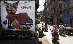 Nepalese travel past a mural in Kathmandu on August 20, 2013. Nepal's capital has been given a facelift thanks to a team of artists who have painted dozens of elaborate and metres-high murals on walls around the Himalayan city/AFP 