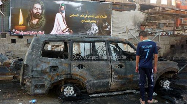 An Iraqi boy inspects a burnt out vehicle the day after a bombing in the Sadr City district of Baghdad on September 22, 2103/AFP