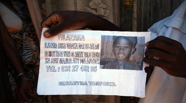 A person holds on October 4, 2013 a leaflet with a photo of Nomena, an 8-year-old boy found dead in Helleville at Nosy Be/AFP
