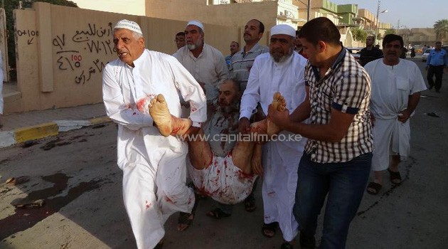 People carry a wounded man at the scene of a car bomb after it exploded as worshippers were leaving a Sunni mosque in Kirkuk, northern Iraq on October 15, 2013/AFP
