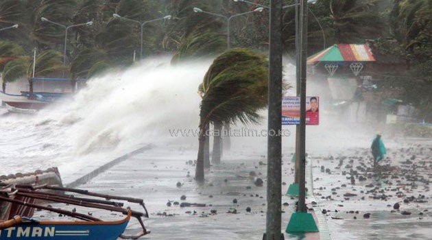 A resident walks past high waves pounding the sea wall amid strong winds as Typhoon Haiyan hit the city of Legaspi in Albay province, south of Manila on November 8, 2013/AFP