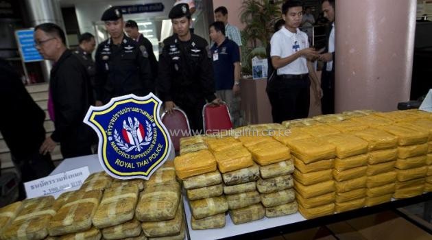 Policemen stand guard next to confiscated packages of amphetamine pills during a press conference at the Narcotics Suppression Bureau in Bangkok on February 3, 2014/AFP