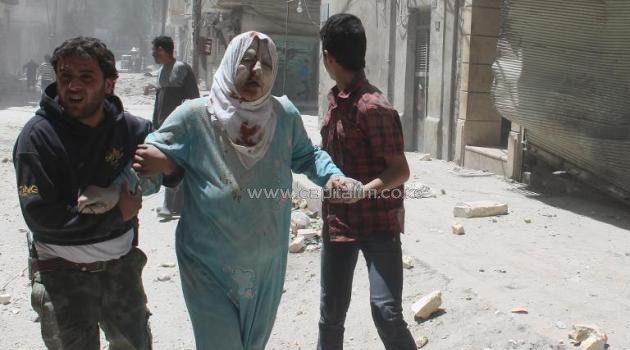 Syrian residents help an injured woman following reported air strikes by pro-regime forces in Aleppo's Al-Qatarji neighborhood, on May 18, 2014/AFP