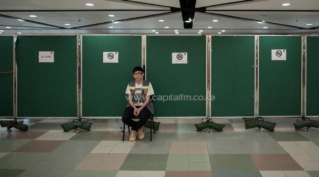 A volunteer sits outside a polling station in Hong Kong on June 22, 2014/AFP