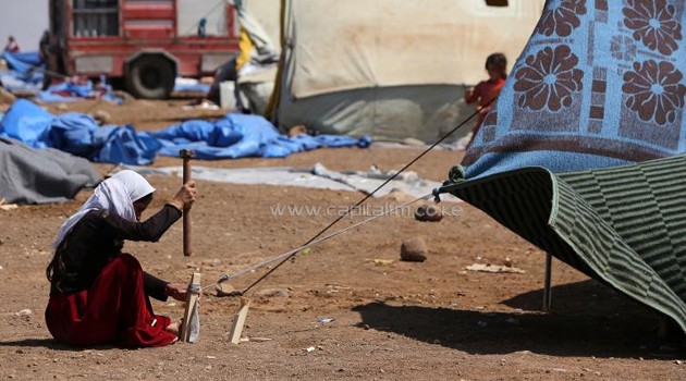 An Iraqi Yazidi refugee woman erects a tent at Newroz camp in Hasaka province, north eastern Syria on August 14, 2014, after fleeing Islamic State militants in Iraq/AFP