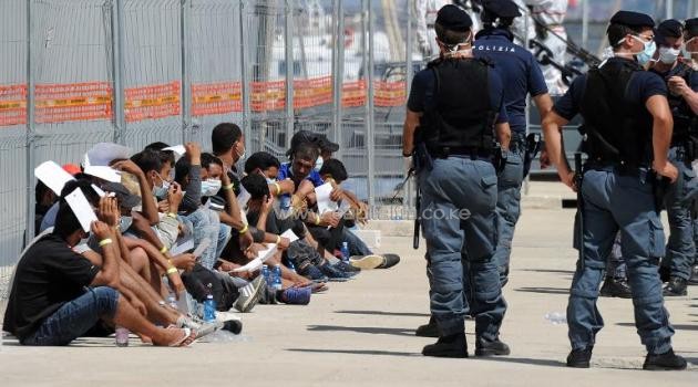 Immigrants wait after they disembarked from the Italian military ship "San Giusto" on August 11, 2014 in the port of Reggio Calabria following a rescue operations at sea/AFP