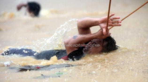 Residents cross a road with strong current as heavy rains brought by Tropical Storm Fung-Wong flood homes at Tumana village in Marikina City on September 19, 2014/AFP