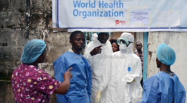 Health workers in protective gear stand at the entrance of the Ebola treatment unit of the John F. Kennedy Medical Center, in the Liberian capital Monrovia, on October 13, 2014/AFP