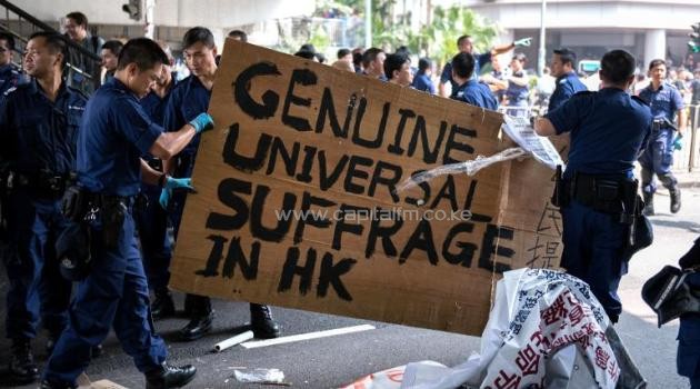 Police remove a sign that calls for "Genuine Universal Suffrage in HK" as they dismantle a pro-democracy protest barricade in Hong Kong, on October 14, 2014/AFP