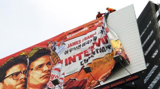 Workers remove the poster for "The Interview" from a billboard in Hollywood, California on December 18, 2014/AFP
