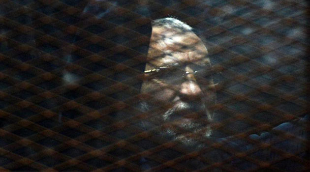 Egyptian Muslim Brotherhood leader Mohamed Badie stands behind bars during his trial at the non-commissioned police officers institute in Cairo/AFP