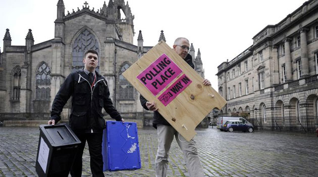Polling Manager Scott Russel (R) and assistant Ross Clement deliver ballot boxes and a sign to a polling station on The Royal Mile in the centre of Edinburgh on May 6 2015 © AFP