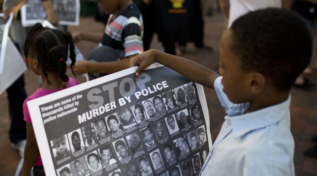 Children look at posters calling for an end to police violence in Baltimore, Maryland on May 10, 2015/AFP