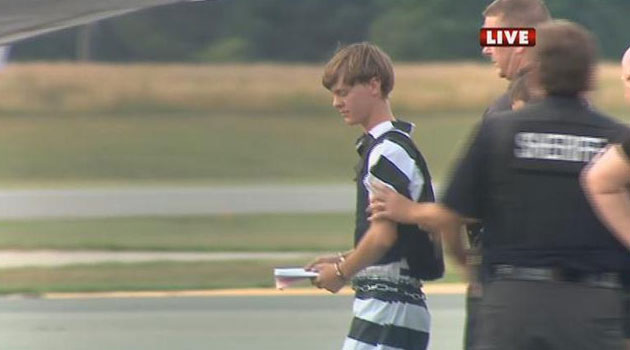 A WBTV News image shows shooting suspect Dylann Roof being escorted by police at the Shelby-Cleveland County Regional Airport for extradition back to Charleston, South Carolina on June 18, 2015/AFP