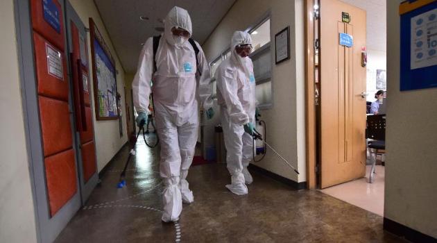 South Korean health officials spray an antiseptic solution while wearing protective gear at an arts centre in Seoul on June 12, 2015/AFP  