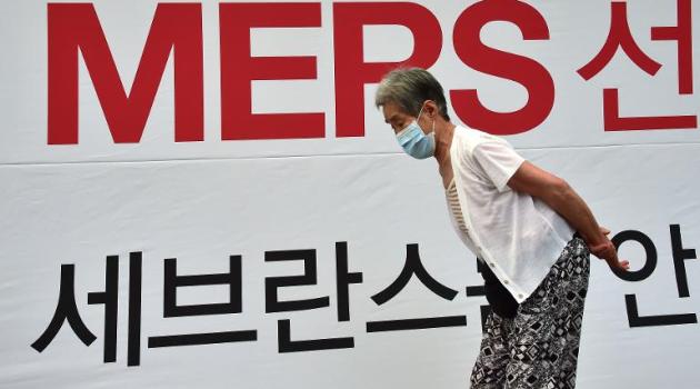 An elderly woman walks past signage on MERS at Severance Hospital in Seoul on June 16, 2015/AFP  