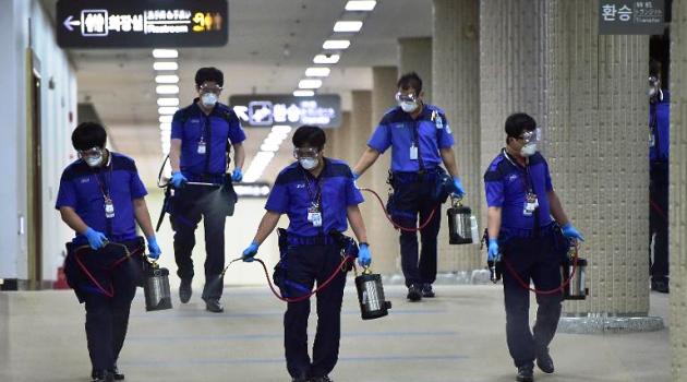 Workers spray antiseptic solution at the customs, immigration and quarantine office of Gimpo international airport, in Seoul, on June 17, 2015/AFP  