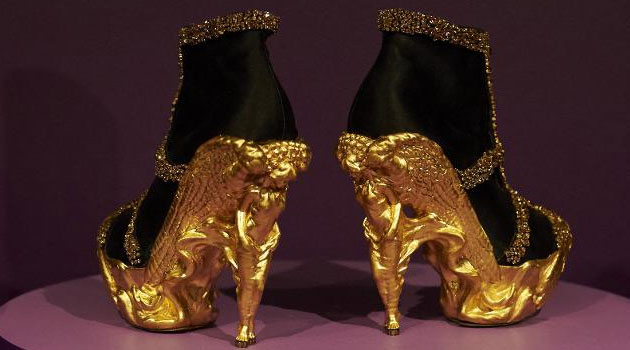 A pair of gold shoes, created by British designer Alexander McQueen, sit on display of an exhibition entitled 'Shoes: Pleasure and Pain', at the Victoria and Albert Museum in central London © AFP