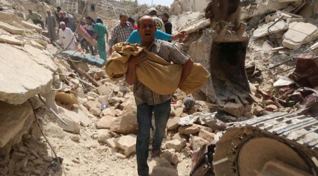 A Syrian man carries a body after a reported barrel bomb attack by regime forces on the northern city of Aleppo, on May 20, 2015/AFP  