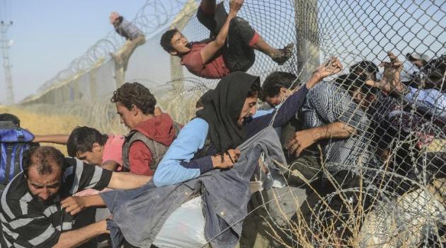 Syrians fleeing the war pass through broken down border fences to enter Turkish territory illegally, near the Turkish Akcakale border crossing in the southeastern Sanliurfa province, on June 14, 2015/AFP  