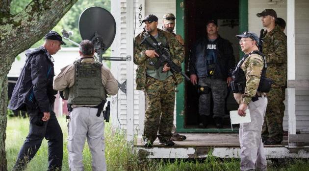 A task force of US Marshalls and police officers go door to door searching for two escaped convicts on June 16, 2015 outside Dannemora, New York/AFP 