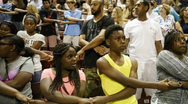 People sing "We Shall Overcome" during a vigil at TD Arena for victims of the recent church shooting in Charleston, South Carolina on June 19, 2015/AFP  