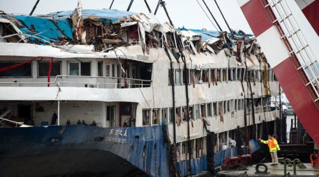 A Chinese rescue worker throws flowers into the river to pay respect to the victims of the Eastern Star disaster after a memorial service in front of the raised cruise ship, in Jianli on June 7, 2015/AFP  