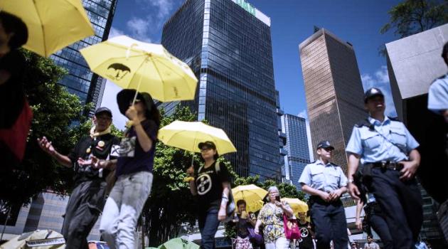 Pro-democracy campaigners hold yellow umbrellas as they march against the government's controversial electoral roadmap, outside the city's legislature in Hong Kong on June 17, 2015/AFP  