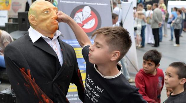 An Ukrainian boy punches a doll representing Russian President Vladimir Putin in a street in Lviv, Ukraine, on May 31, 2015/AFP  