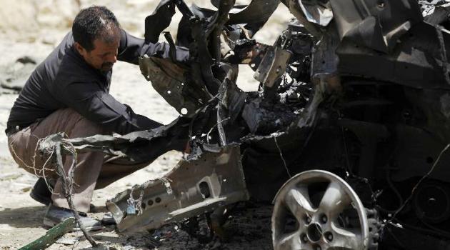 A Yemeni forensic expert in Sanaa on June 18, 2015 inspects wreckage of a car following deadly bombings the previous day/AFP  